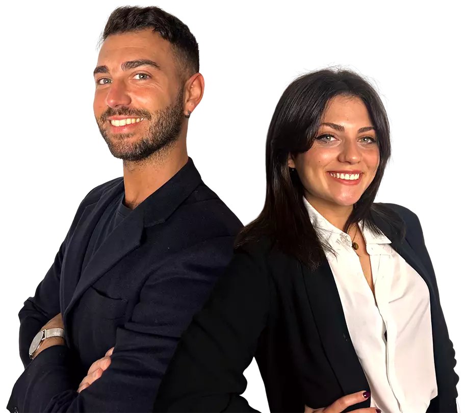 Hombre y mujer con atuendos formales, sonriendo y posando de espaldas entre sí. Fondo negro y expresión segura en sus rostros.