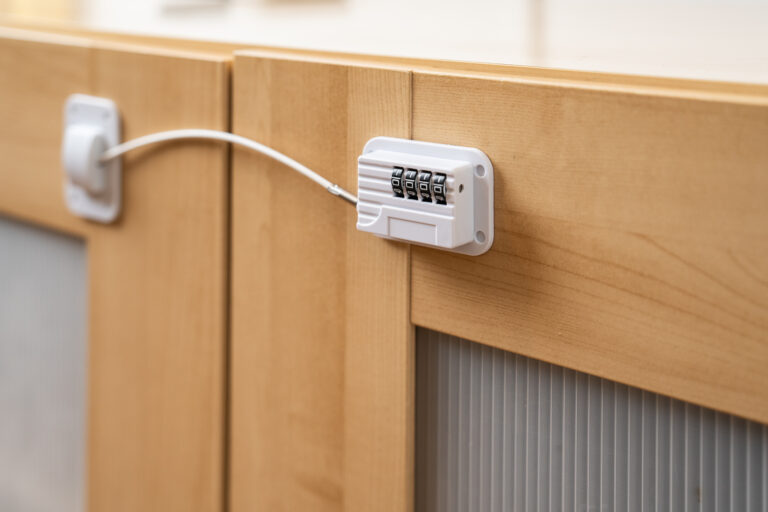 Cerradura de combinación en armario de madera clara, cable de seguridad conecta las puertas, superficie superior lisa.